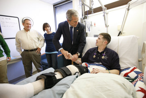 President George W. Bush shakes hands with U.S. Army Staff Sgt. Kyle Stipp of Avon, Ind., after presenting him with two Purple Hearts Monday, Dec. 22, 2008, during a visit to Walter Reed Army Medical Center where the soldier is recovering from wounds suffered in Operation Iraqi Freedom. Looking on are his wife, Megan, and father, Mitch Stipp. White House photo by Eric Draper