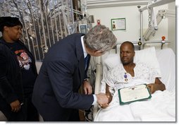 President George W. Bush shakes the hand of U.S. Army Sgt. First Class Neal Boyd of Haynesville, La., after presenting him a Purple Heart during a visit Monday, Dec. 22, 2008, to Walter Reed Army Medical Center, where the soldier is recovering from injuries received in Operation Iraqi Freedom. Looking on his SFC Boyd's wife, Joyce. White House photo by Eric Draper