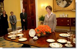 Mrs. Laura Bush meets reporters as she announces two new White House china patterns, Wednesday, Jan. 7, 2009 in the Family Dining Room of the State Floor of the White House for their unveiling of the George W. Bush State China and the Magnolia Residence China. The George W. Bush State China was inspired from a Madison-era dinner service. The Magnolia Residence China is in the picture foreground and the George W. Bush State China is on the left side of the table. With Mrs. Bush from left are Amy Zantsinger, White House Social Secretary, Nancy Clarke, White House Florist, and Bill Allman, White House Curator. White House photo by Shealah Craighead