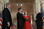 President George W. Bush watches Thursday, Sept. 29, 2005 in the East Room of the White House in Washington, as Judge John G. Roberts is sworn-in as the 17th Chief Justice of the United States by Associate Supreme Court Justice John Paul Stevens. Judge Roberts' wife Jane is seen holding the Bible.