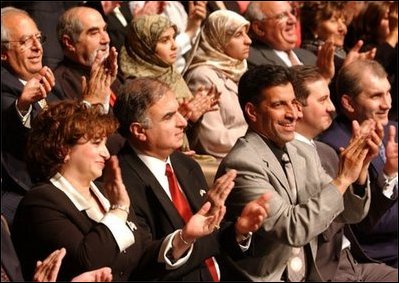 Standing at the far right, Haider Al-Jebori, President of the Steering Committee for Iraqi Home Culture, applauds for President George W. Bush at the Ford Community and Performing Arts Center in Dearborn, Mich., Monday, April 28, 2003. 
