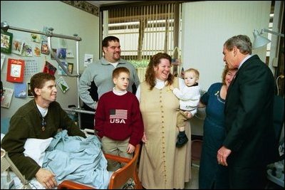 President George W. Bush embraces the mother-in-law of U.S. Army Staff Sergeant Roy Mitchell, who is at left, as other family members look on during the President’s visit to Walter Reed Army Medical Center in Washinton, D.C., Thursday, December 18, 2003. President Bush had just presented Sgt. Mitchell The Purple Heart for injuries sustained while serving in Iraq. Sgt. Mitchell is from Milan, Indiana. Others present are, from left, Jerry Stoneking, Zachary Bice and Sgt. Mitchell's wife, Michelle, who is holding their son Jerrett.