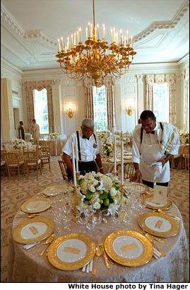 White House Butlers James Ramsey and Buddy Carter check over place settings in the State Dining Room. More than a dozen tables of Millennium China were set for guests. White House photo by Tina Hager.