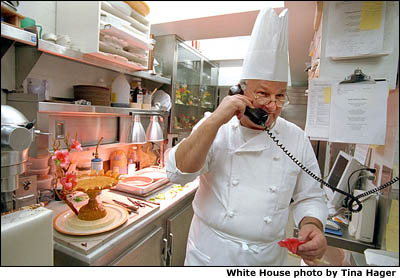 Breaking for a call, Pastry Chef Roland Mesnier prepares the evening's dessert, a mango and coconut ice cream dome with Peaches. White House photo by Tina Hager.