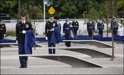 Soldiers hold ceremonial clothes that were draped over the 184 memorial benches, each honoring all innocent life lost when American Airlines Flight 77 crashed into the Pentagon on Sept. 11, 2001, during the dedication of the 9/11 Pentagon Memorial Thursday, Sept. 11, 2008, in Arlington, VA.