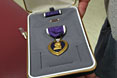 A wounded soldier displays his autographed Purple Heart after being awarded the medal by Vice President Dick Cheney at Walter Reed Medical Center in Washington, October 22, 2003. Initially created as the Badge of Military Merit by General George Washington, the Purple Heart is the oldest military decoration in the world in present use and the first American award made available to the common soldier.