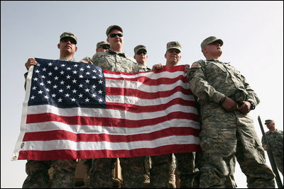 U.S. troops hold the American flag as they await Vice President Dick Cheney's arrival to a rally Tuesday, March 18, 2008 at Balad Air Base, Iraq.