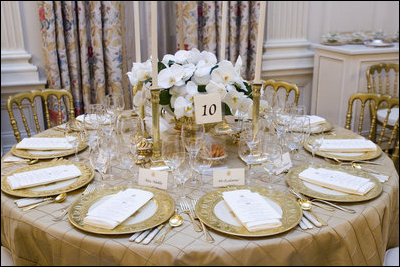 The table settings in the State Dining Room for the White House dinner Wednesday, Nov. 2, 2005, in honor of the Prince of Wales and Duchess of Cornwall.  Chosen by Mrs. Laura Bush, the centerpieces are sprays of white phaeleanopsis orchids displayed in vermeil vases and compliment the Clinton China and vermeil flatware.  