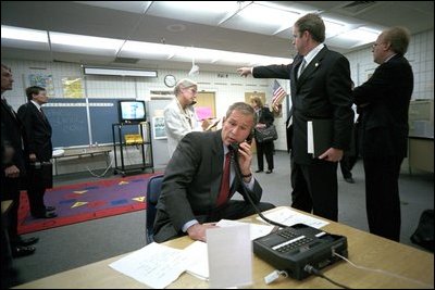 As then-Deputy Assistant Dan Bartlett points to news footage of the World Trade Center, President Bush gathers information about the attack from Emma E. Booker Elementary School in Sarasota, Fla., Sept. 11, 2001. 