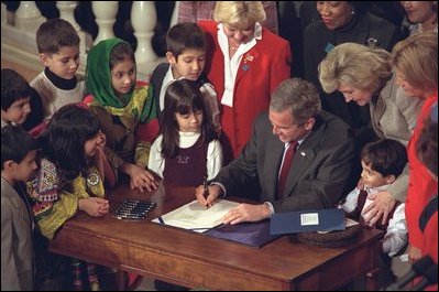 President Bush signs the Afghan Relief Act, East Room, Dec. 12, 2001.