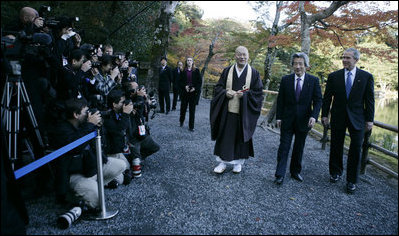 President George W. Bush and Japan’s Prime Minister Junichiro Koizumi join the Reverend Raitei Arima, Chief Priest of the Golden Pavilion Kinkakuji Temple in Kyoto, as they walk past the press during a cultural visit to the temple Wednesday, Nov. 16, 2005.