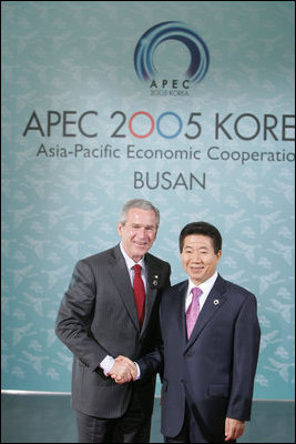 President George W. Bush shakes hands with President Moo Hyun Roh of the Republic of Korea as President Roh welcomes him to the 2005 APEC conference in Busan.