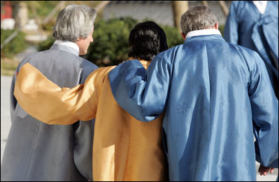 Robed in traditional garb, President George W. Bush walks arm-in-arm with Japan's Prime Minister Junichiro Koizumi, right, and Peru's President Alejandro Toledo outside the Nurimaru APEC House in Busan, Korea, Saturday, Nov. 19, 2005, for the APEC official photograph.
