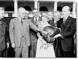 Photograph of President Truman receiving a Thanksgiving turkey from members of the Poultry and Egg National Board and other representatives of the turkey industry, outside the White House.