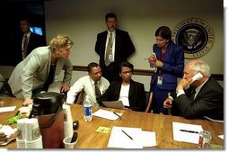 As Vice President Dick Cheney talks on the phone, Karen Hughes listens with fellow White House staff members in the Presidential Emergency Operations Center Sept. 11, 2001. White House photo by David Bohrer.