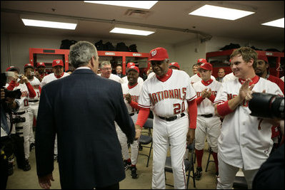 President George W. Bush shakes the hand of veteran player and Manager Frank Robinson Thursday, April 14, 2005, as members of the Washington Nationals, including left fielder Brad Wilkerson, right, applaud.  The President tossed the ceremonial first pitch at the season opener that marked the return of baseball to the nation's capitol.