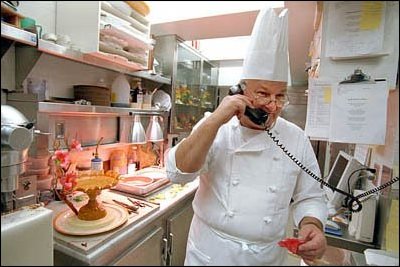 Breaking for a call, Pastry Chef Roland Mesnier prepares dessert, a mango and coconut ice cream dome with peaches, for the state dinner honoring Mexican President Fox, September 5, 2001.