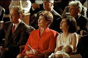 Georgetown University President John J. DeGioia, Laura Bush, and Theresa DeGioia, who is holding young J.T. DeGioia, listen to speakers at the White House Summit on Early Childhood Cognitive Development at Georgetown University. (July 26-27, 2001)