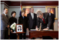 President George W. Bush signs a condolence book for the victims of the recent tsunami during a visit to the Embassy of Thailand in Washington, D.C., Monday, Jan. 3, 2005. Next to the book, stands a photograph of Khun Poom Jensen, 21. A grandson of Thailand's King Bhumibol Adulyadej, Mr. Jensen died in the tsunami. Also signing their condolences are Laura Bush and former Presidents Bush and Clinton. 