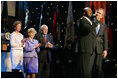 President George W. Bush puts his arm around Singer Bebe Winans as he sings 'God Bless America' during the 'Saluting Those Who Serve' event at the MCI Center in Washington, D.C., Tuesday, Jan. 18, 2005. Also pictured are, from left, Laura Bush, Lynne Cheney, and Vice President Dick Cheney. 