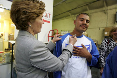 Laura Bush signs the shirt of a member of Homeboy Industries in Los Angeles April 27, 2005. Homeboy Industries is an job-training program that educates, trains and finds jobs for at-risk and gang-involved youth.