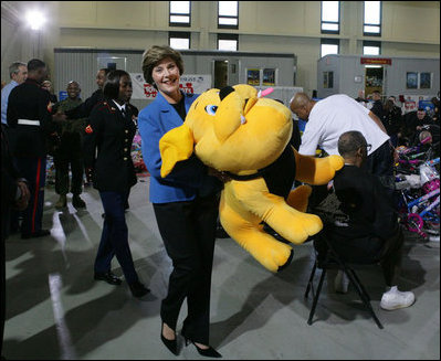 Mrs. Laura Bush helps carry a large stuffed animal to a toy distribution vehicle, Monday, Dec. 19, 2005, at the "Toys for Tots" collection center at the Naval District Washington Anacostia Annex in Washington, D.C., where she joined President George W. Bush in thanking the U.S. Marines for their charitable efforts.