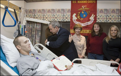 As Laura Bush looks on, President George W. Bush hugs Candy Pierson of Auburndale, Fla., after her son, Marine Cpl Jordan S. Pierson, was presented the Purple Heart for injuries suffered while serving in Iraq. The ceremony took place Wednesday, Dec. 21, 2005, at the National Naval Medical Center in Bethesda, Md. Also in the room are Cpl. Pierson's fiancée, Kirstin Martin, right, and cousin Tiffany Pierson.