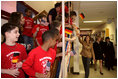 Laura Bush reaches for the hands of children waving U.S. and German flags as she passes them in the hallway of the Hainerberg Elementary School February, 22, 2005, in Wiesbaden, Germany.