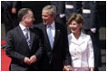 President George W. Bush and Laura Bush walk with Scotland's First Minister Jack McConnell during the playing of national anthems upon their arrival at Glasgow's Prestiwick Airport, July 6, 2005.