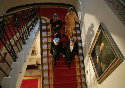 President George W. Bush, Laura Bush and India's Prime Minister Dr. Manmohan Singh and Mrs. Gursharan Kaur walk down the stairs to the State Dining Room, Monday, July 18, 2005 at the White House, for the official dinner in honor of the visit by India's Prime Minister Dr. Manmohan Singh.