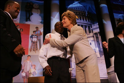 Laura Bush attends the Opening Session of the 2005 National Big Brothers Big Sisters Conference, June 9, 2005, at the Marriott Wardman Park Hotel. Washington, D.C. On-stage participants include: Vincent "Vinny" Thomas, Big Brother, left, ; and Parry Elliott, Little Brother, 13-years-old, being embraced by Mrs. Bush.