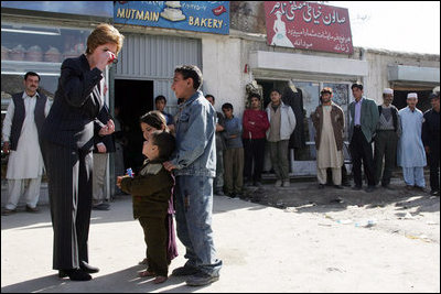 Laura Bush shows youngsters how to use a kaleidoscope outside a Kabul bakery after a stop Wednesday, March 30, 2005. The toys were gifts from the White House given by the first lady during her brief visit to Afghanistan.