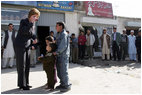 Laura Bush shows youngsters how to use a kaleidoscope outside a Kabul bakery after a stop Wednesday, March 30, 2005. The toys were gifts from the White House given by the first lady during her brief visit to Afghanistan.