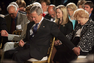 President George W. Bush and Laura Bush holds hands with guests while praying during a ceremony observing the National Day of Prayer in the East Room Thursday, May 5, 2005.