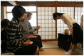 Mrs. Laura Bush accepts a cup of tea from a student in the Tea Ceremony Classroom at Doshisha Girls Junior High School and Senior High School during her visit Wednesday, Nov. 16, 2005, to Kyoto, Japan. With Mrs. Bush are Susanne Schieffer, wife of U.S. Ambassador Thomas Schieffer, and Mrs. Hanayo Kato, wife of Japanese Ambassador Ryozo Kato.