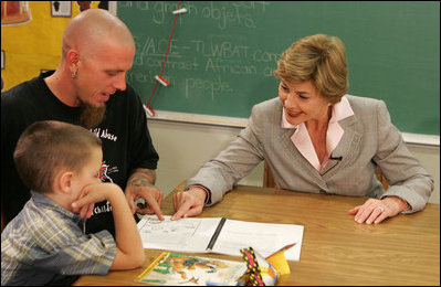 Laura Bush works with a child and father, while participating in the R.E.A.D. to Kids Training Program at J.S. Chick Elementary School in Kansas City, Mo., Tuesday, October 11, 2005.