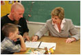 Laura Bush works with a child and father, while participating in the R.E.A.D. to Kids Training Program at J.S. Chick Elementary School in Kansas City, Mo., Tuesday, October 11, 2005.