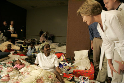 Laura Bush leans down to comfort a woman and her young child inside the Cajundome at the University of Louisiana in Lafayette, Friday, Sept. 2, 2005, during her visit to the center, one of many created to accommodate victims of Hurricane Katrina.