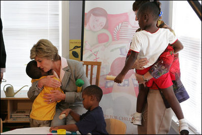Mrs. Laura Bush receives a hug from a young boy at the House of Tiny Treasures in Houston during her visit Monday, Sept. 19, 2005. The House enables parents to search for jobs and housing, and to run errands while their children receive good care from credentialed teachers.