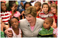 Mrs. Laura Bush embraces two students Monday, Aug. 28, 2006, as she meets and speaks with members of the Gorenflo Elementary School first grade class in their temporary portable classroom at the Beauvoir Elementary School in Biloxi, Miss. The students, whose school was damaged by Hurricane Katrina, are sharing the facilities of the Beauvoir school until their school’s renovations are complete.