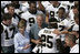 President George W. Bush and Laura Bush are surrounded by members of the New Orleans Saints football team Tuesday, Aug. 29, 2006, as they point out the name of Saints star rookie running back Reggie Bush, when the team met President Bush at the New Orleans Airport to pose for a team photo.