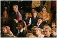 President George W. Bush and Mrs. Laura Bush sit with children of deployed U.S. military personnel and watch a performance of "Willy Wonka" by members of The Kennedy Center Education Department in the East Room Monday, Dec. 4, 2006. 