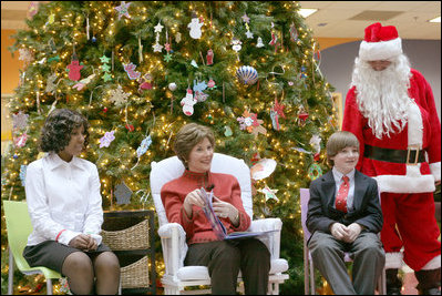 Mrs. Laura Bush sits with patient escorts Allison Meads, left, and Matthew Morgan, as she reads to an audience of children, patients and hospital staff Friday, Dec. 8, 2006, at The Children's National Medical Center in Washington, D.C., where Mrs. Bush visited with patients and debuted the 2006 Barney Cam video.