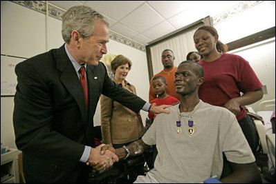 President George W. Bush shakes the hand of SSgt. Marcus Wilson after awarding him two Purple Hearts at the Walter Reed Army Medical Center in Washington, D.C., Friday, Dec. 22, 2006, as Mrs. Laura Bush and members of the Marine's family look on. Wilson, who is from Dermott, Arkansas, is recovering from wounds suffered in Operation Iraqi Freedom. 