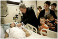 President George W. Bush presents a Purple Heart to Sgt. John Kriesel of Twin Cities, Minn., during a visit Friday, Dec. 22, 2006, to Walter Reed Army Medical Center where the National Guardsman is recovering from injuries suffered in Operation Iraqi Freedom. Looking on with Mrs. Laura Bush is Sgt. Kriesel's wife, Katie, holding their 4-year-old son Broden and 5-year-old son Elijah.