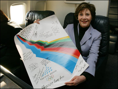 Mrs. Laura Bush shows her signatured 2006 Winter Olympic poster during her flight home from Italy, Feb. 12, 2006.