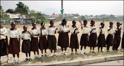 Students at Model Secondary School in Abuja, Nigeria, wave American flags as they line the street during a visit by Laura Bush Wednesday, Jan. 18, 2006.