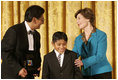 Laura Bush congratulates Jose Fernando Salas, left, and Carlos Gabriel Pascual from the Art and Children Program of Veracruz, Mexico, at their award presentation Wednesday, Jan. 25, 2006 in the East Room of the White House, during the President's Committee on the Arts and the Humanities 2006 Coming Up Taller Awards ceremony.