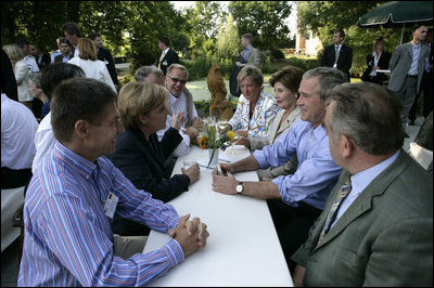 President George W. Bush shares a conversation with Chancellor Angela Merkel of Germany as he and Mrs. Laura Bush enjoy a barbeque dinner in Trinwillershagen as guests of the Chancellor.