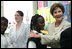 Mrs. Laura Bush congratulates Our Lady of Perpetual Help School student Rajanique White, 10, Monday, June 5, 2006, for the story Rajanique wrote and recited about a small accident that happened to her. Mrs. Bush visited the school to announce a Laura Bush Foundation for America's Libraries grant to Our Lady of Perpetual Help.